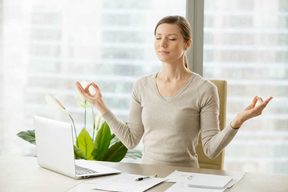 Žena v práci, která si prochází stresem a frustrací, medituje